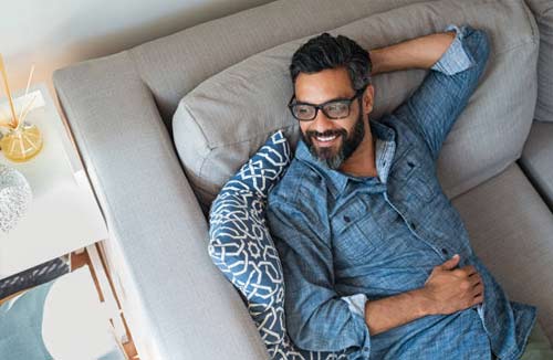 man smiling sitting on his couch