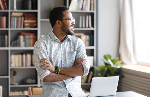 man looking out the window at his desk