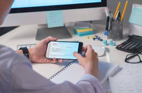 person photographing a check with their smartphone